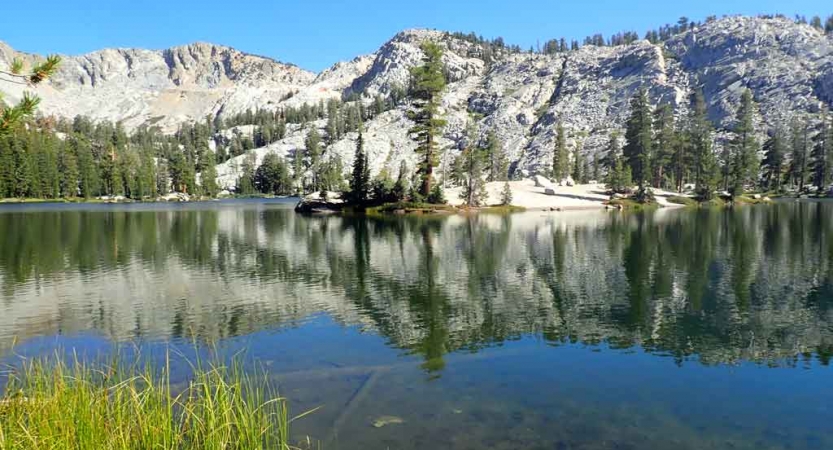 a body of water lies among trees and hills in yosemite